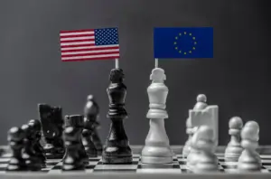 Due re degli scacchi, uno nero e uno bianco, con bandierine di USA e Unione Europea, contrapposti su una scacchiera