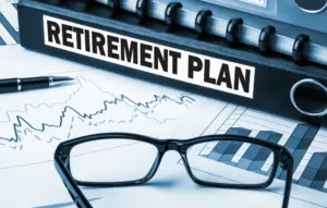 Raccoglitore con etichetta "Retirement plan", penna, occhiali e grafici su fogli con andamenti a linee e barre in tonalità blu.